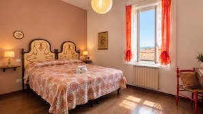 Une chambre à coucher avec un lit, des lampes de chevet, une fenêtre avec des rideaux et un radiateur.