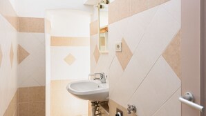 Een badkamer met een wastafel, spiegel en betegelde wanden.