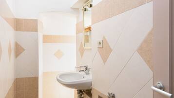 Un baño con lavabo, espejo y paredes con azulejos.