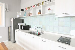 Una cocina moderna con armarios blancos, un refrigerador de acero inoxidable, un microondas y un lavabo con grifo.