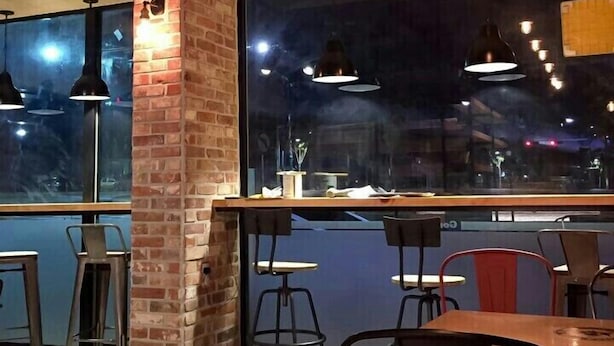 A modern interior with exposed brick walls, large windows, and a mix of metal and wooden furniture. - Nangman Sea (Yeosu)