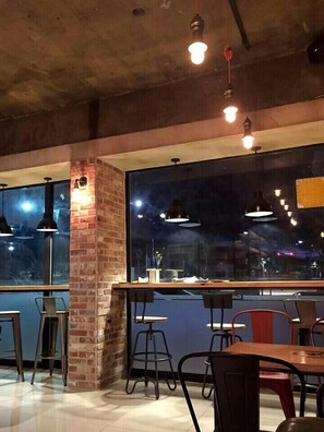 A modern interior with exposed brick walls, large windows, and a mix of metal and wooden furniture. - Nangman Sea (Yeosu)