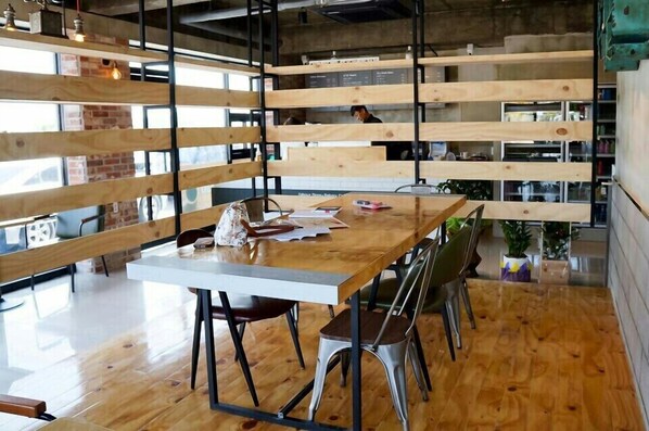 A modern dining area with a wooden table, metal chairs, and a brick wall.