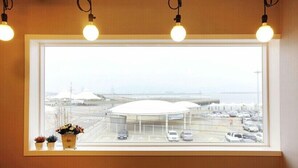 A window with a view of a parking area and a building with a dome-like structure. - Nangman Sea (Yeosu)