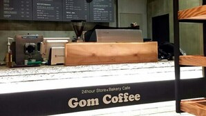 A 24-hour store and bakery cafe named Gom Coffee with a coffee machine and menu boards. - Nangman Sea (Yeosu)