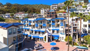 A multi-story hotel with balconies, a parking area, and a golf cart service. - Seaport Village Inn Avalon (Avalon)