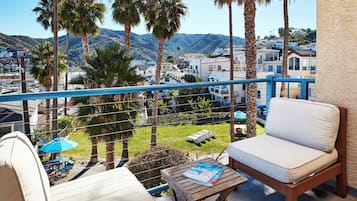 A balcony with a white sofa, a wooden table, and a blue umbrella.