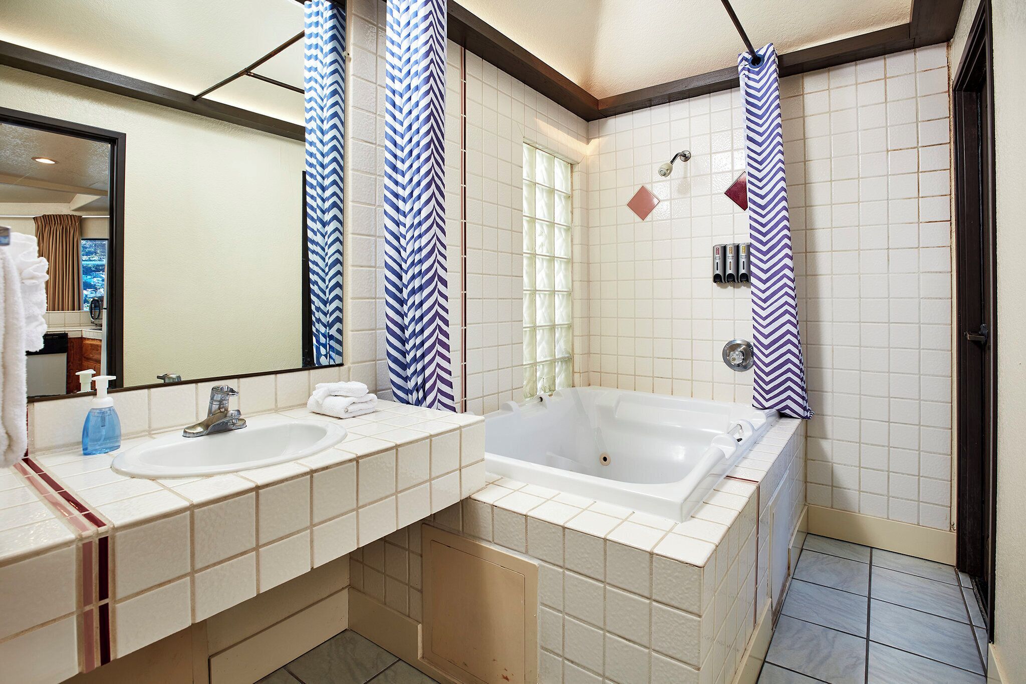 Un baño con lavamanos doble, una bañera grande y un espejo.