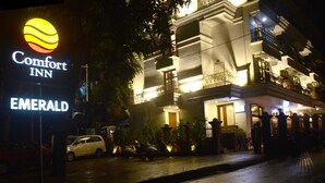 Um hotel chamado Comfort Inn Emerald, com uma placa bem visível, um edifício de vários andares com sacadas e carros estacionados na rua.