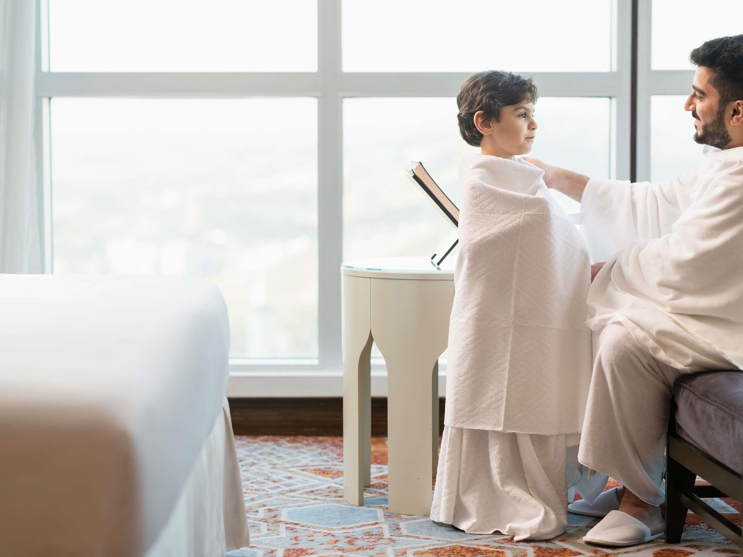 Une pièce avec un lit, une petite table sur laquelle se trouve un livre et une grande fenêtre.