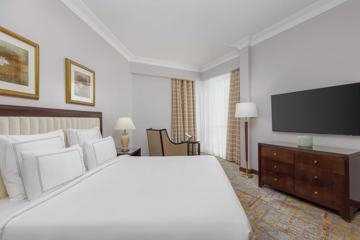 Een hotelkamer met een groot bed, een televisie, een bureau en een stoel.