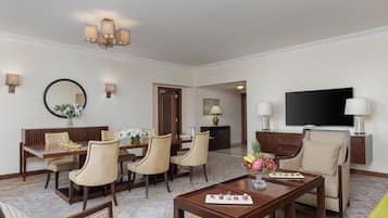 A hotel room with a dining area, a TV, and a seating area with a coffee table.