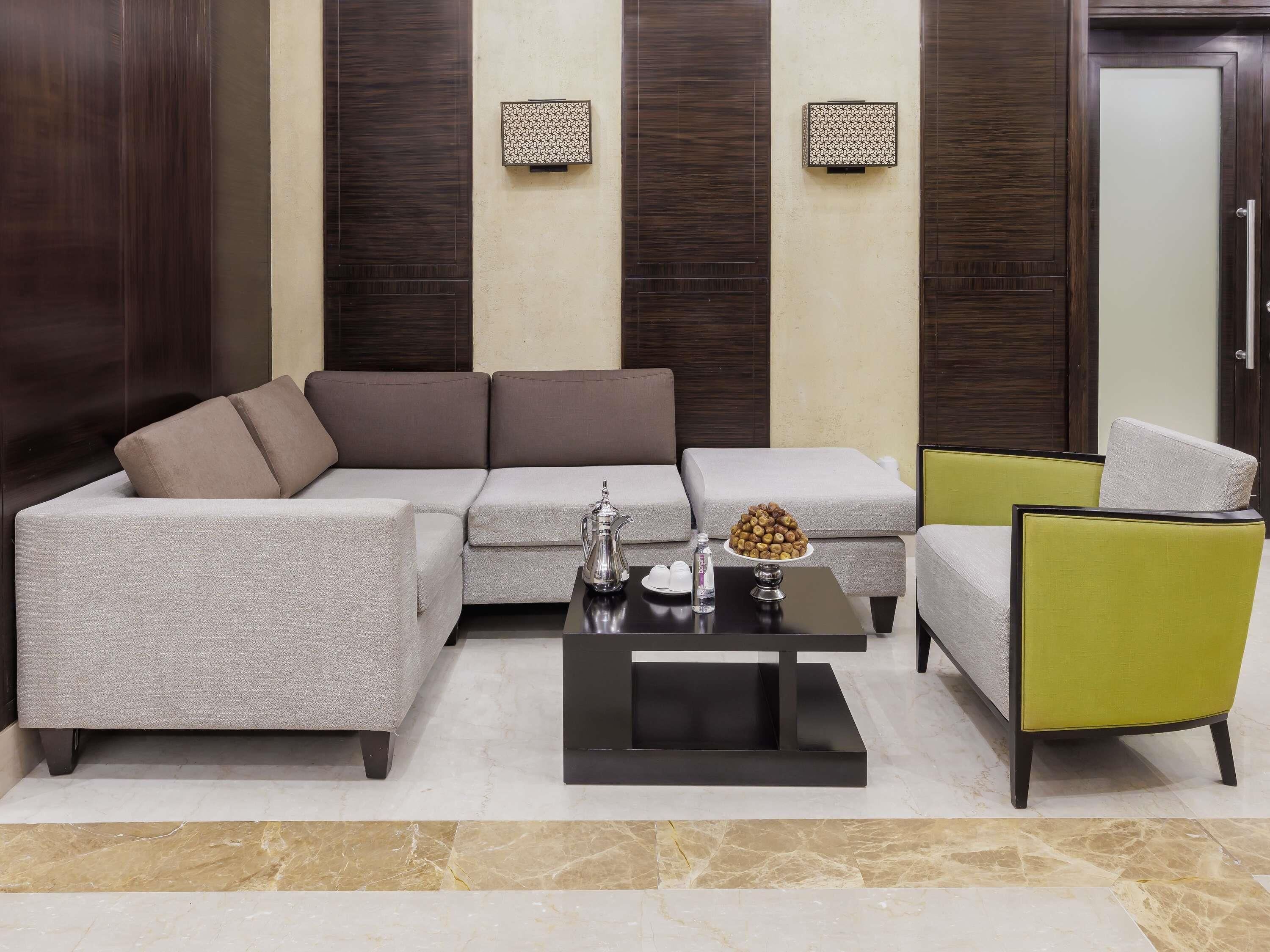 A modern living room with a sectional sofa, a coffee table, and a green armchair.