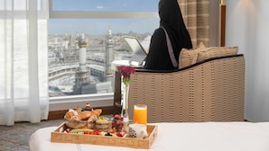 Une chambre d’hôtel avec un lit, une table où est servi le petit-déjeuner, un ordinateur portable et une vue sur le paysage urbain.