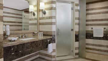 Une salle de bain moderne avec un meuble-lavabo en marbre, une cabine de douche en verre et des carreaux muraux à rayures.