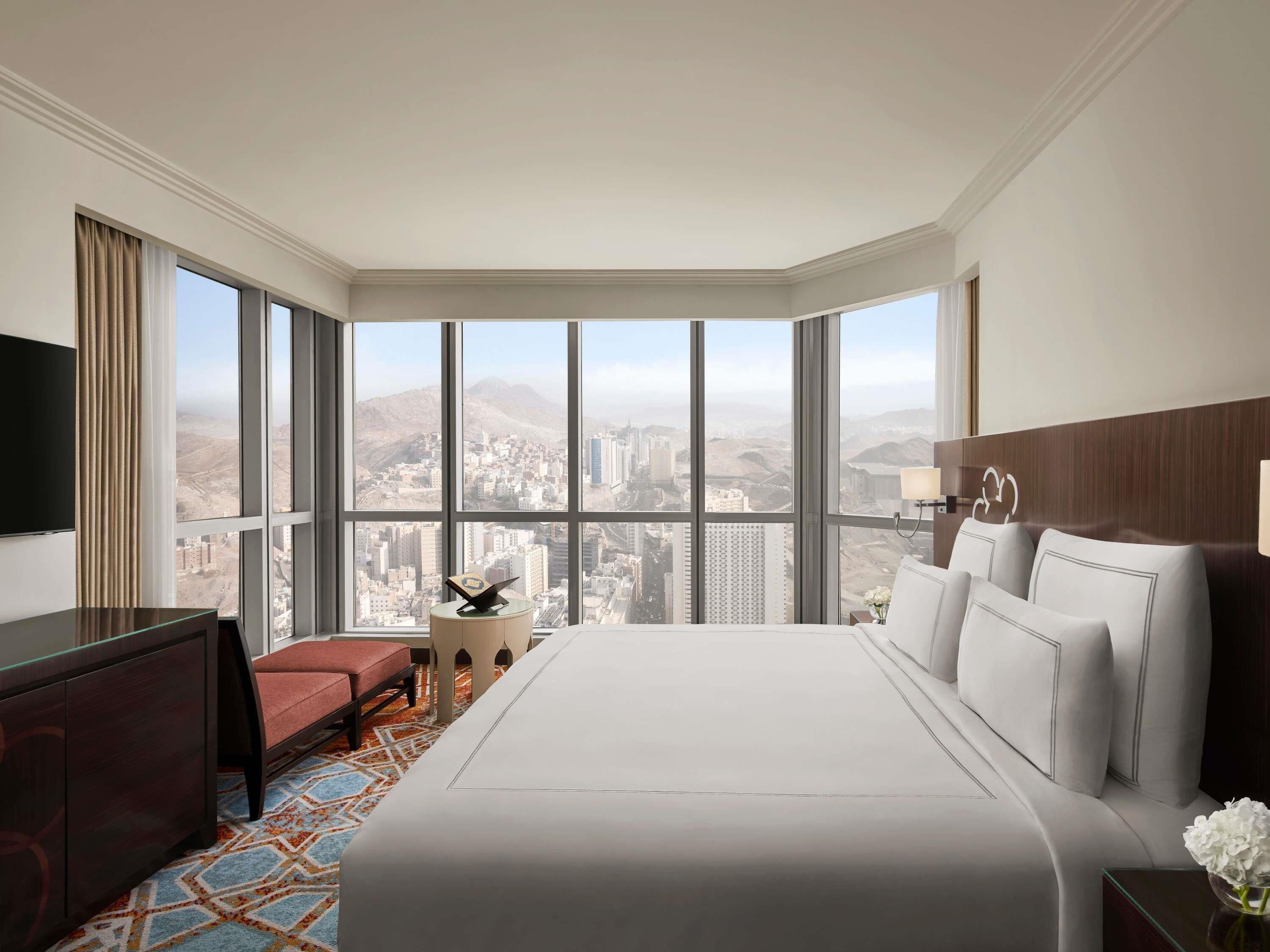 Une chambre d’hôtel avec un grand lit, un bureau, une chaise, une télévision et une vue sur le paysage urbain.