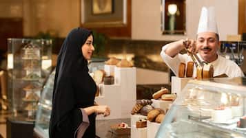 A bakery display case with various pastries and a person in chef attire.
