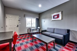 Un salon moderne avec un canapé, une table à manger et un tapis aux motifs rouges et noirs.