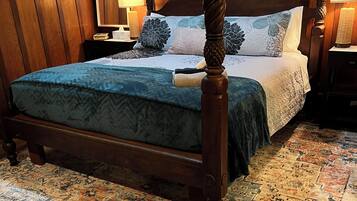 A four-poster bed with a dark wooden frame and a patterned bedspread.