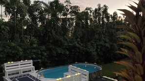 A swimming pool with a deck, surrounded by greenery. - Hilo Bay Oceanfront B&B (Hilo)