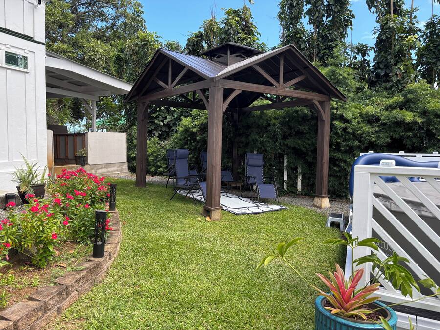Ein überdachter Patio-Bereich mit einer Pergola, Sitzgelegenheiten im Freien und einem Pool.
