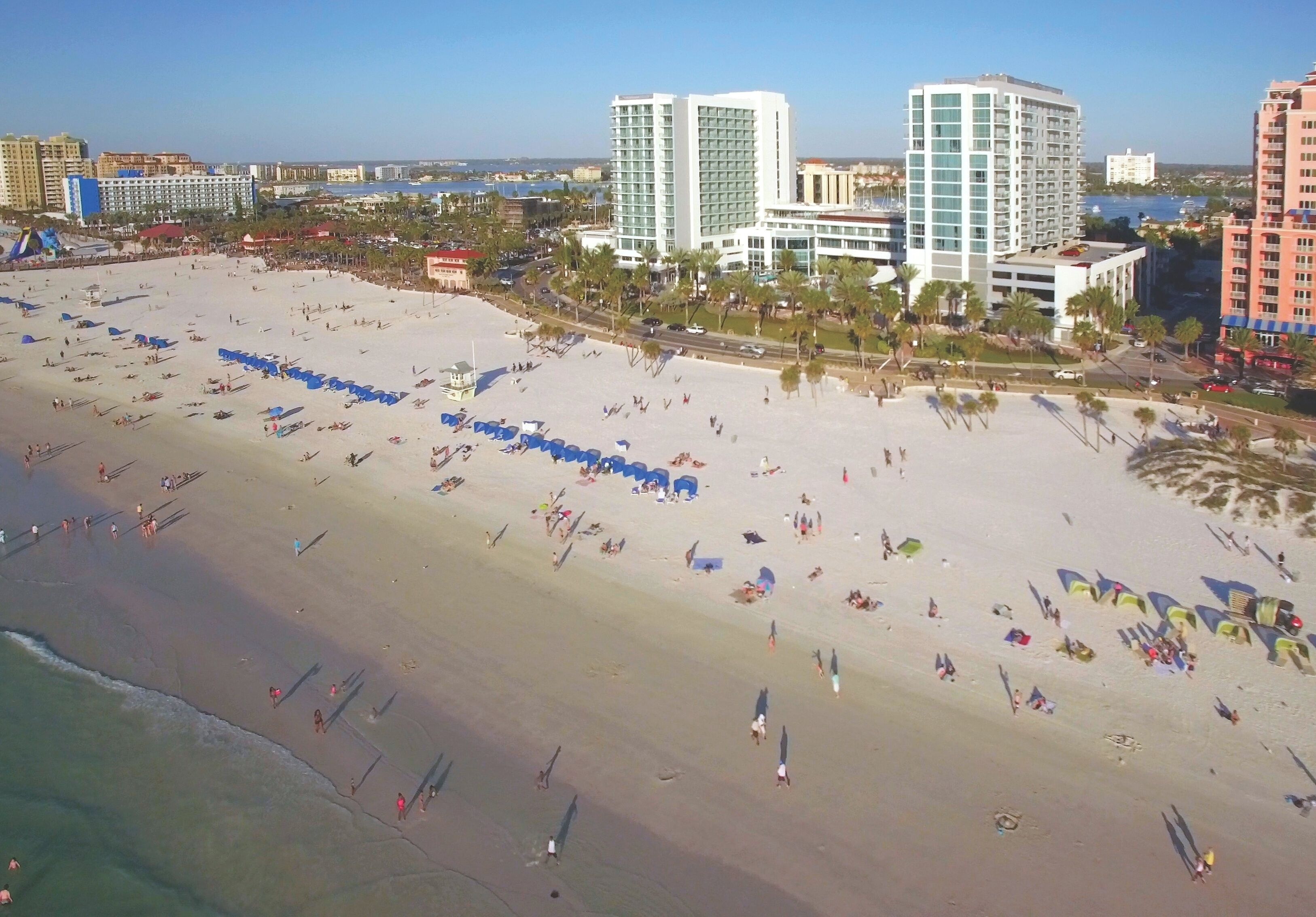A beach with rows of umbrellas and people.