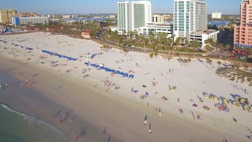 A beach with rows of umbrellas and people.