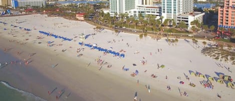 Une plage bordée de rangées de parasols et où se trouvent de nombreuses personnes.