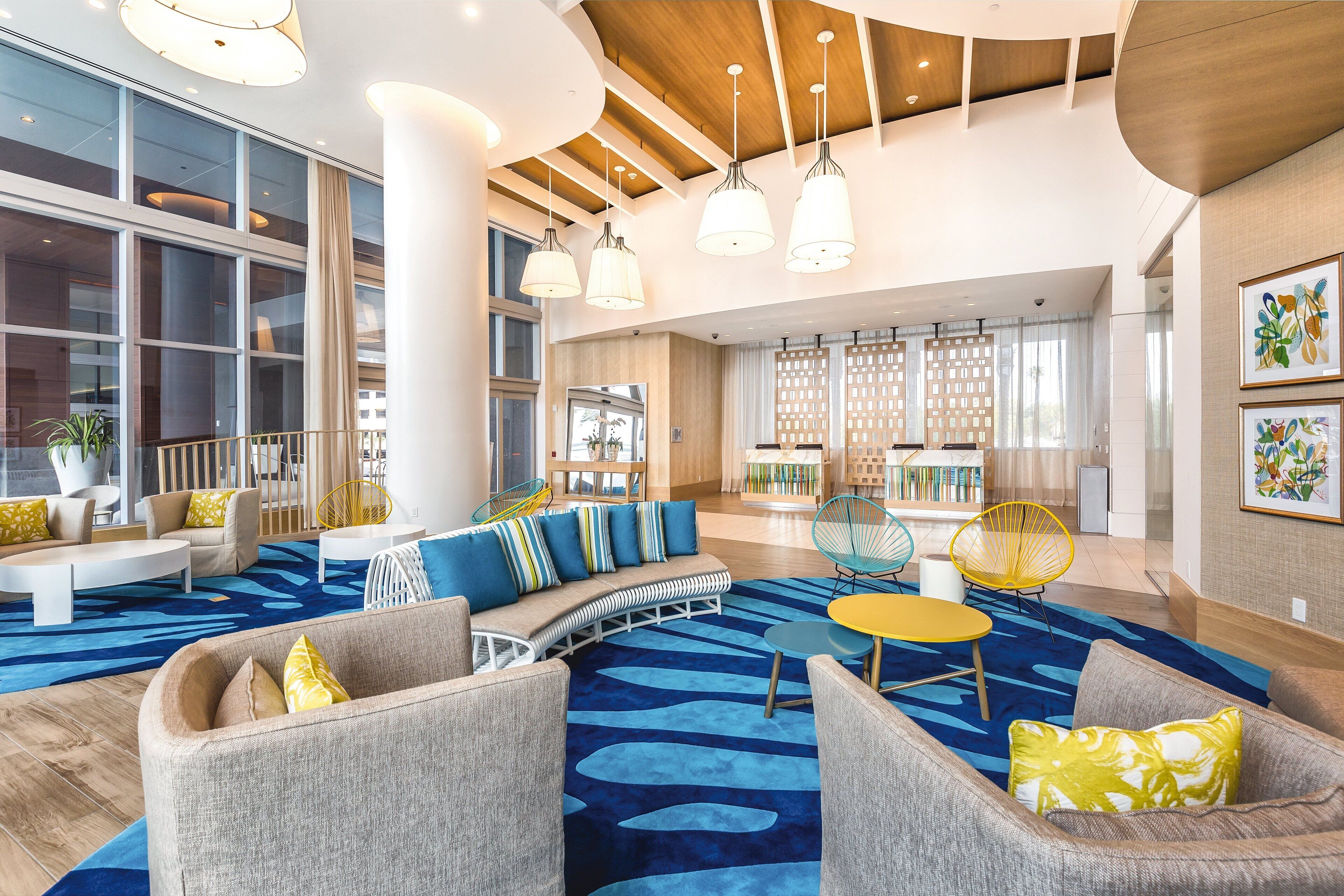 A spacious lobby with a blue patterned carpet, modern furniture, and large windows allowing natural light.