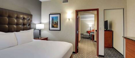 A hotel room with a large bed, a nightstand, a lamp, a framed picture on the wall, and a mirror.