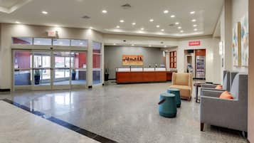 A hotel lobby with a reception desk, seating area, and a refrigerator.