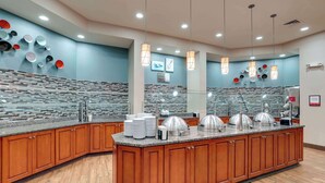 A modern kitchen with a central island, wooden cabinets, and a backsplash with a mosaic tile design.
