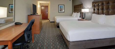 A hotel room with a large bed, a desk with a chair, a television, and a mirror.