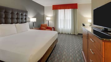 A hotel room with a large bed, a television, a desk, and a chair.
