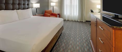 A hotel room with a large bed, a television, a desk, and a chair.