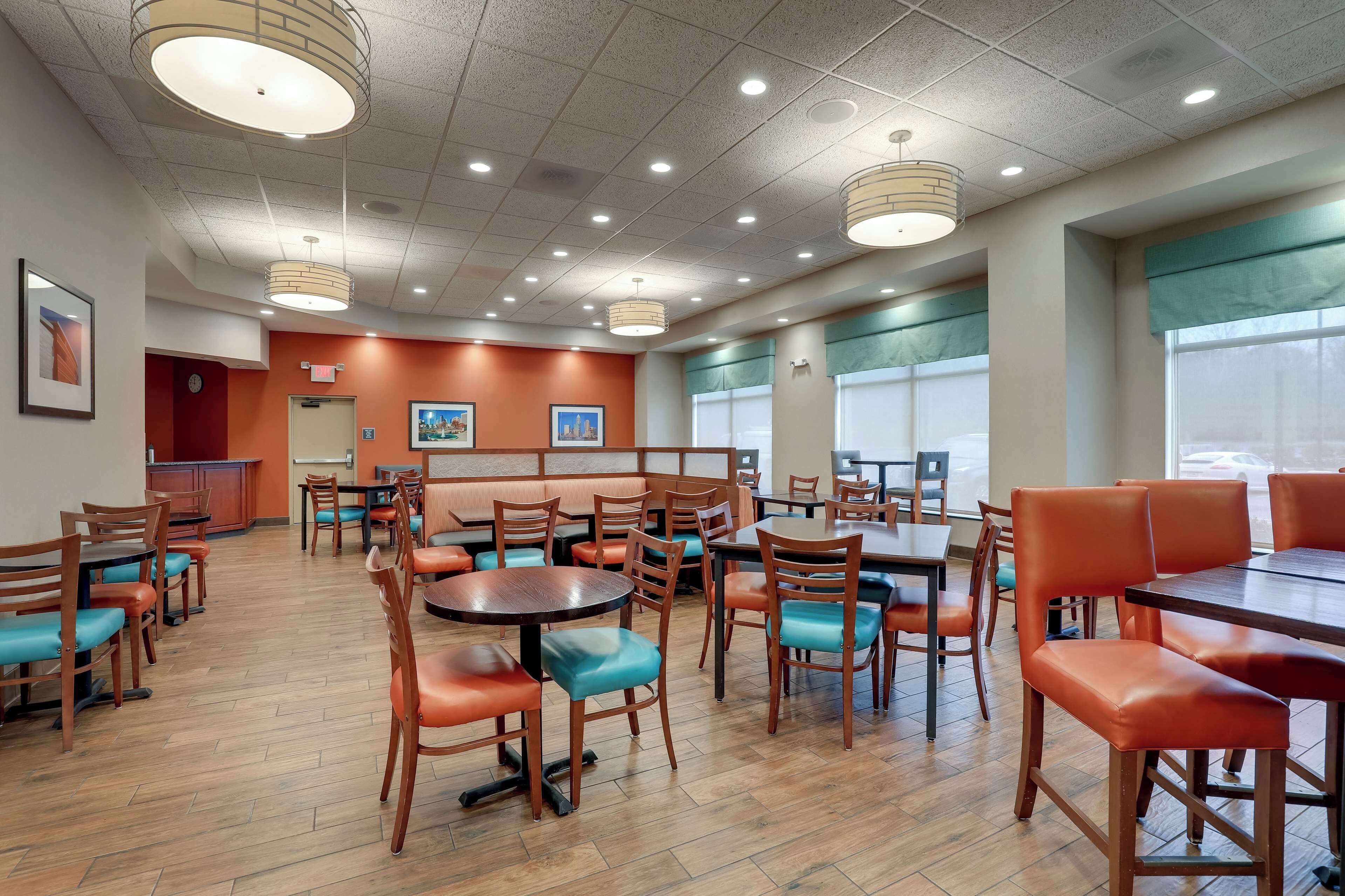 A spacious dining area with multiple tables and chairs, a counter, and a seating area with a view of the outdoors.