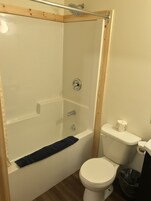 A bathroom with a shower, toilet, and a towel rack.