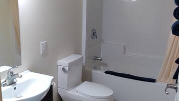Un baño con lavamanos, inodoro y bañera blancos.