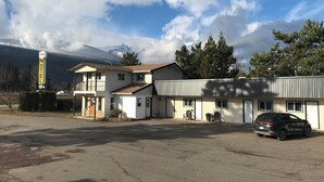 A motel with a two-story building, a parking lot, and a mountain backdrop. - Florence Motel (Smithers)
