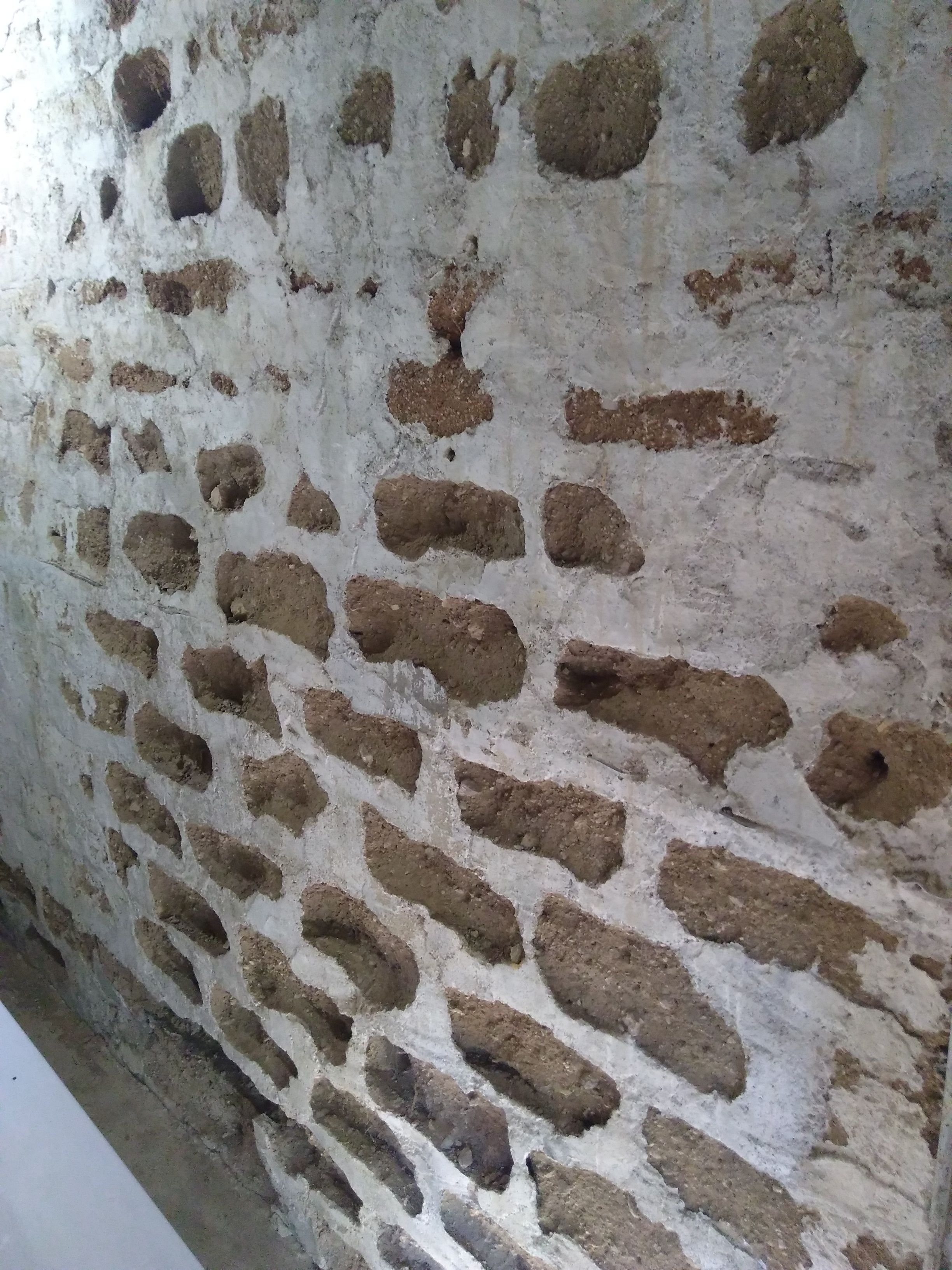 Un mur à la texture irrégulière et rugueuse, probablement fait de pierre ou de briques.