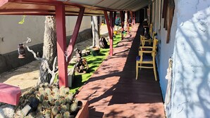 A covered outdoor area with a wooden deck, chairs, and a cactus garden.