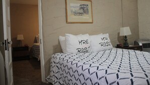 A hotel room with a bed, two bedside tables, a lamp, and a framed picture on the wall.
