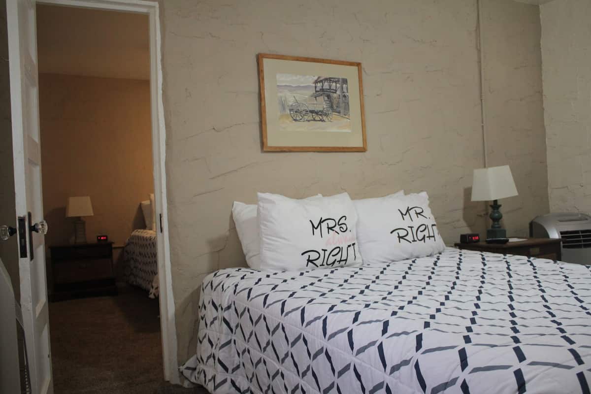 A hotel room with a bed, two bedside tables, a lamp, and a framed picture on the wall.