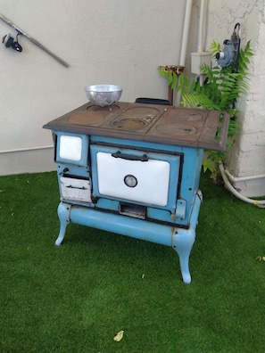 A blue vintage stove with a metal bowl on top, placed on a grassy area. - Historic Shep's Miners Inn near Kingman (Chloride)