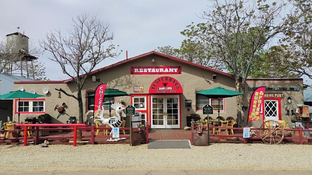 A restaurant with a red exterior, outdoor seating, and a sign indicating it offers food and lodging.