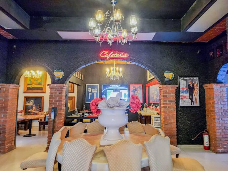 Un café acogedor con un letrero de neón, arcos de ladrillo y una araña.