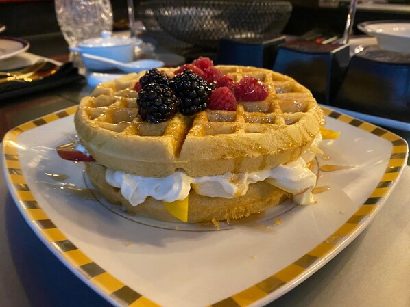A waffle with whipped cream and berries on a plate. - Hotel Black (Mexico City)