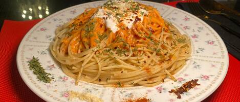 A plate of spaghetti with a creamy sauce, garnished with herbs and spices, on a floral-patterned plate.