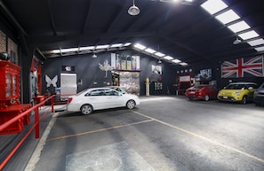 Un lavadero de coches con varios vehículos, un extintor rojo y una bandera británica.