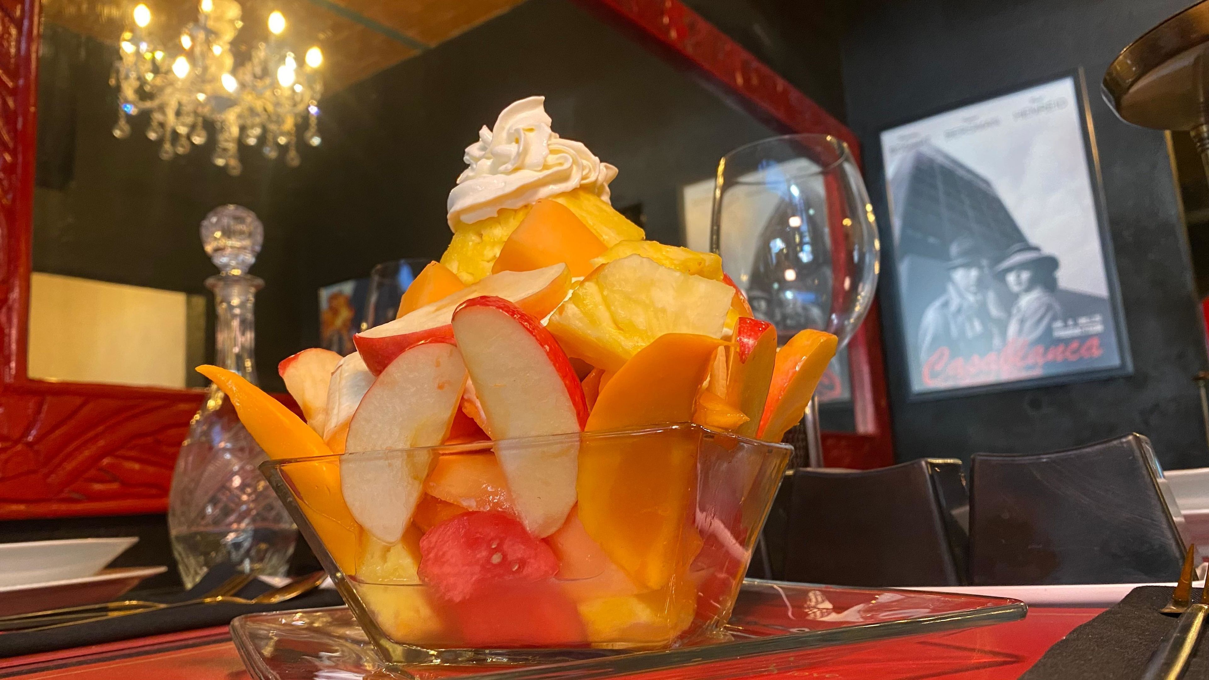 Un dessert servi dans un bol en verre, composé de fruits et de crème fouettée.
